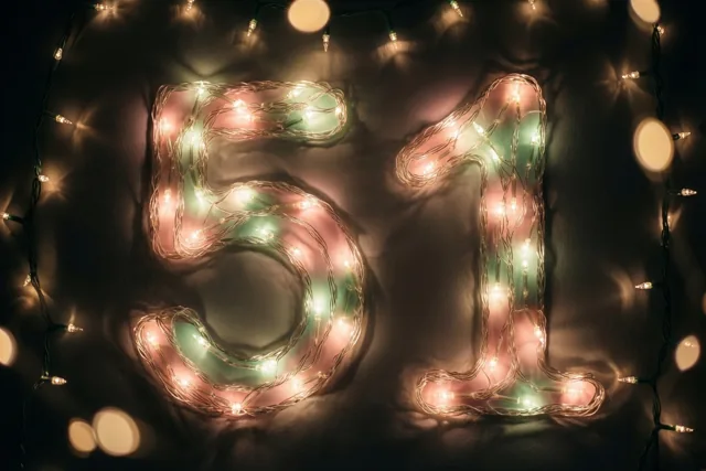 Het getal 51 is gevormd door gloeiende lichtjes op een donkere muur, met zachte onscherpe lichtjes op de achtergrond.