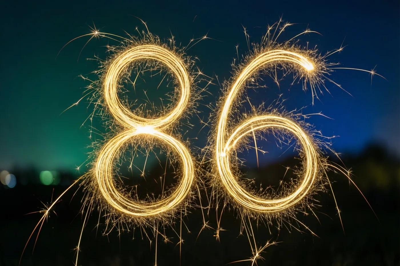 Gouden vonkensporen vormen 86 tegen een donkere nachthemel met een verloop van blauw naar groen.