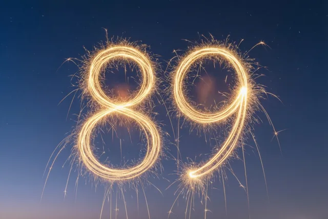 Gouden vonkensporen vormen het getal 89 tegen een donkerblauwe nachtlucht.