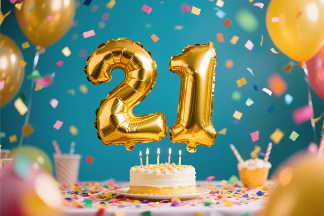Gouden cijferballonnen vormen 21 boven een tafel met confetti en een taartje met brandende kaarsen, met extra ballonnen tegen een blauwgroene achtergrond.