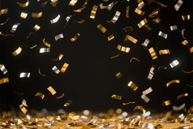 Gouden en zilveren confetti valt tegen een donkere achtergrond en ligt verspreid over de ondergrond vooraan.