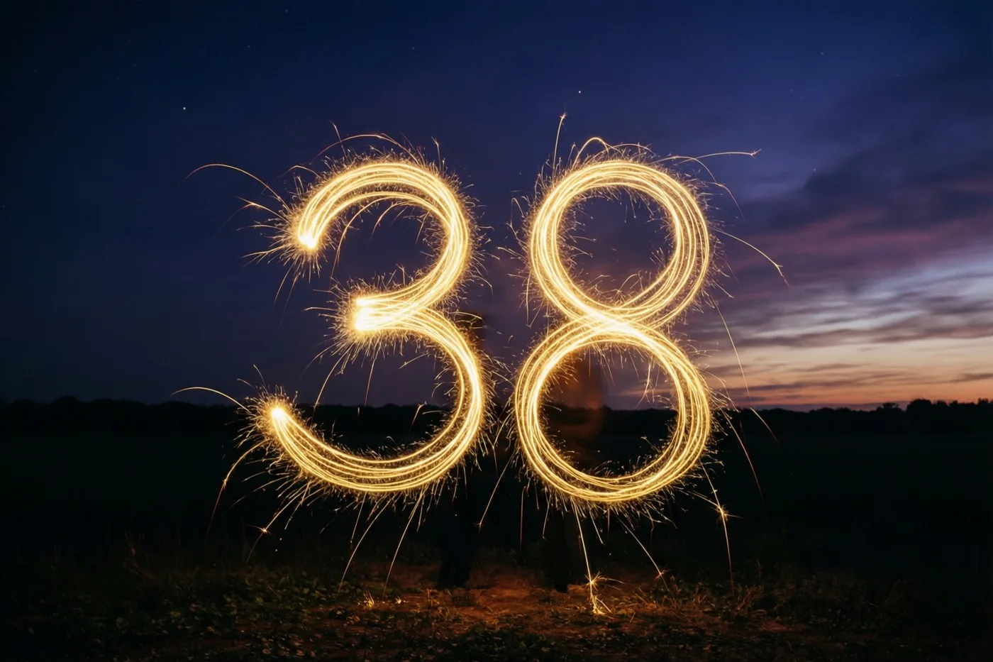 Gouden lichtsporen van sterretjes vormen 38 boven een veld bij schemering, tegen een donkere hemel met een zwakke zonsondergang aan de horizon.