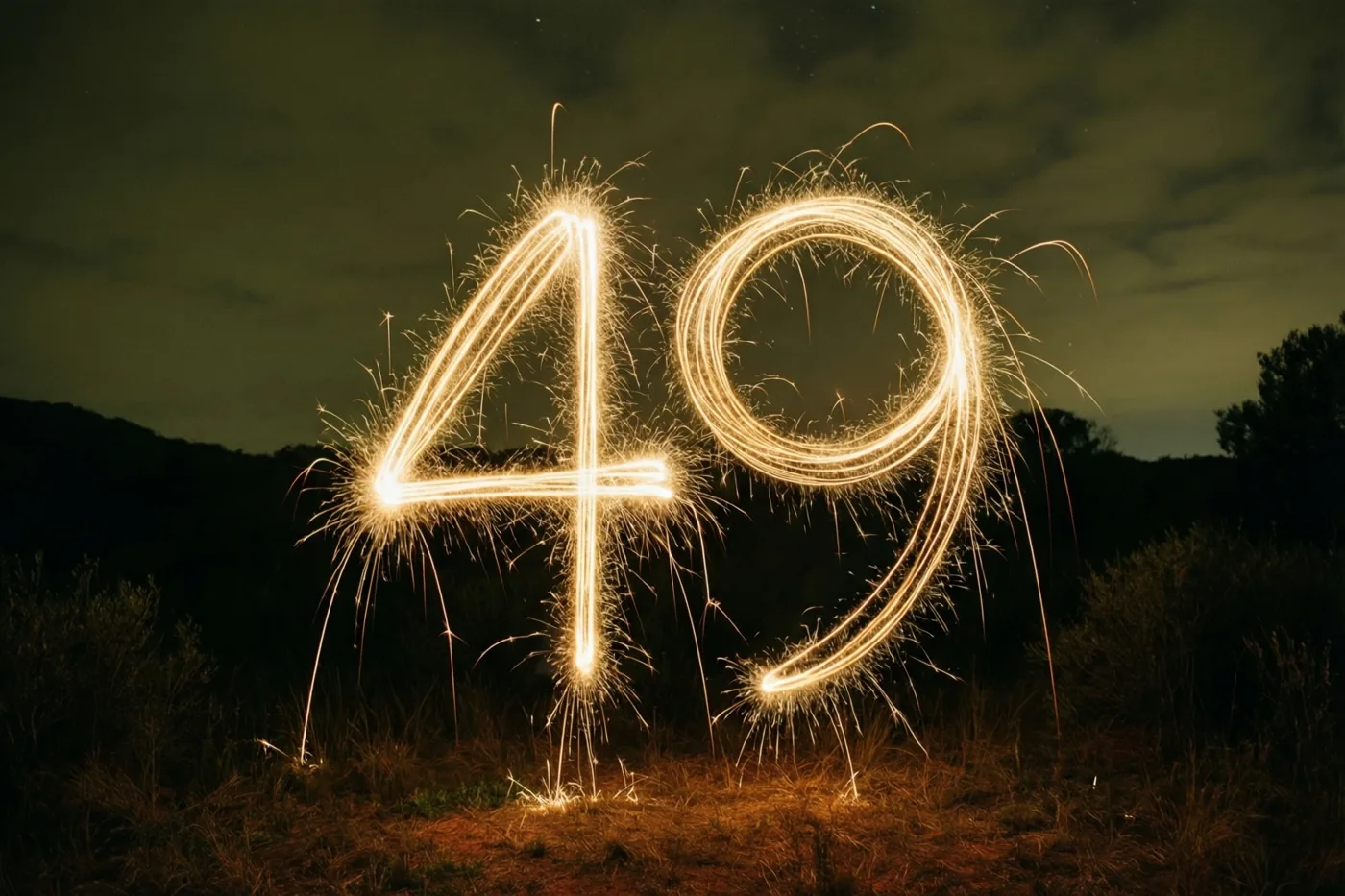 Gouden lichtsporen van sterretjes vormen 49 tegen een donkere nachthemel met heuvels op de achtergrond.