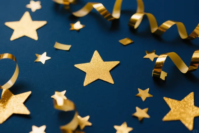 Gouden sterren en krullende confetti liggen verspreid over een donkerblauw oppervlak.