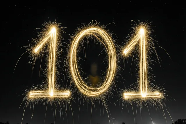 Gouden lichtsporen van sterretjes vormen 101 tegen een zwarte nachtelijke achtergrond.