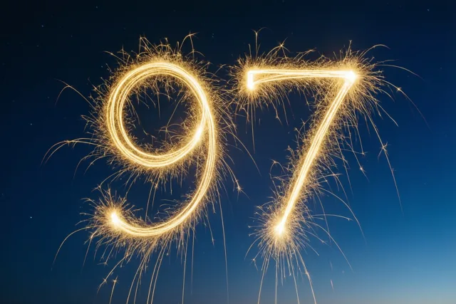 Gouden lichtsporen van sterretjes vormen het getal 97 tegen een donkerblauwe nachtelijke hemel.