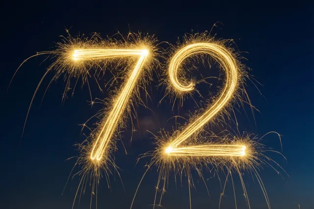 Gouden vonkensporen vormen 72 tegen een diepblauwe nachthemel.