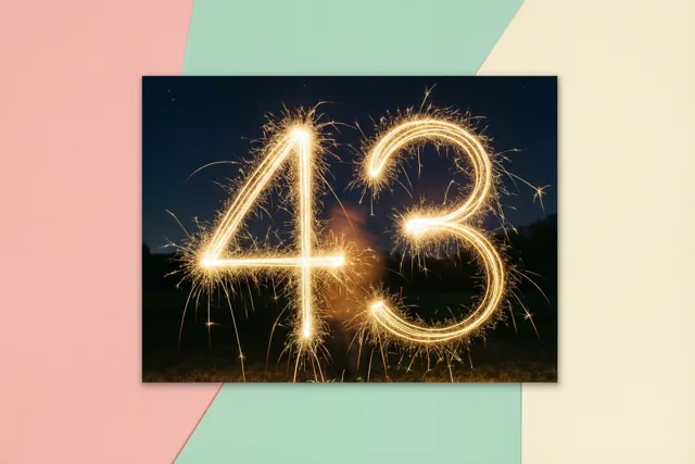 Een ingelijste foto op een pastelkleurige achtergrond toont 43 in gouden lichtsporen van sterretjes tegen een donkere nachthemel.