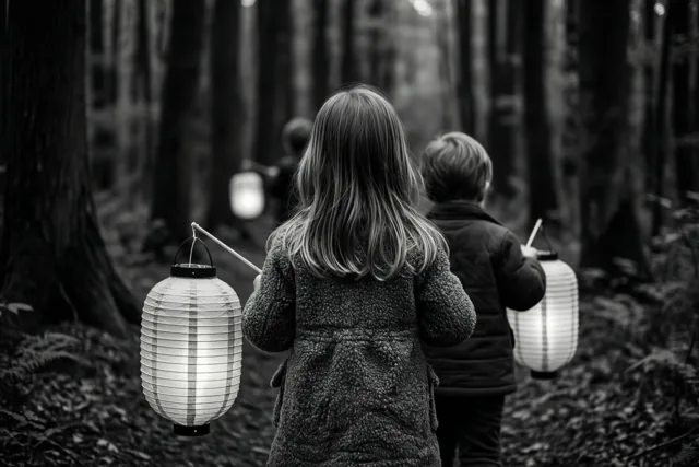 Op een zwart-witfoto lopen kinderen met papieren lantaarns van de kijker weg door een donker bos.