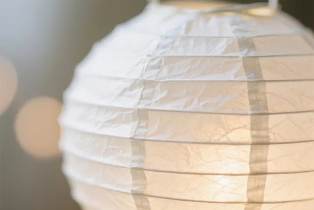 Een close-up toont een lichtgevende papieren lantaarn met duidelijk zichtbare vouwen en plooien in warme tinten.