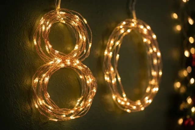 Warme lichtjes vormen het getal 80 tegen een donkere muur met textuur, met zachte, onscherpe lichtvlekken op de achtergrond.