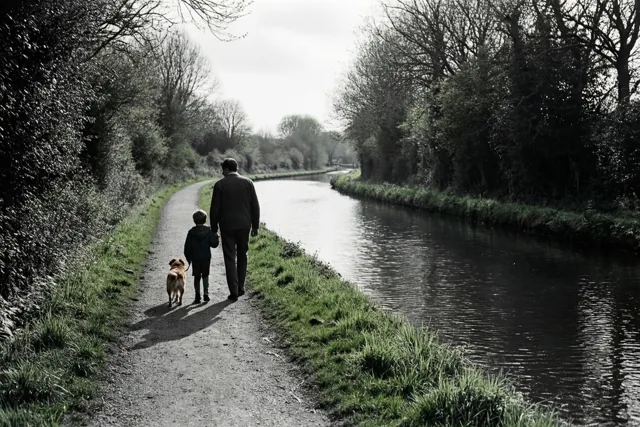Een vader en kind wandelen hand in hand met een hond over een smal jaagpad langs een rustig kanaal, met gras en bomen onder een bewolkte lucht in gedempte kleuren.