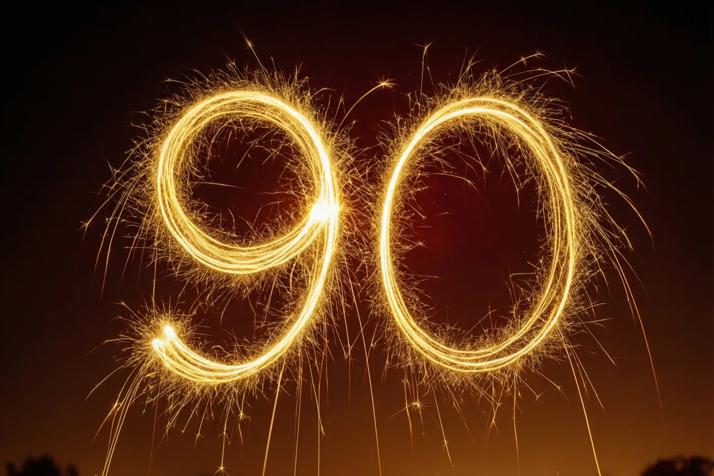 Gouden lichtsporen van sterretjes vormen 90 tegen een donkere nachthemel, met gloeiende gele en oranje tinten.