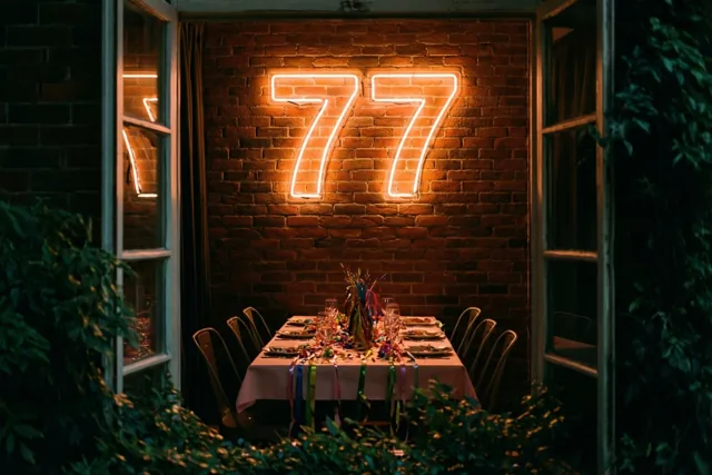 Een warm verlicht neongetal 77 hangt boven een feesttafel met slingers, omringd door open ramen en weelderig groen.