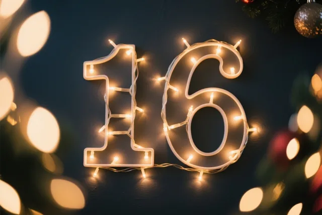 Warme lichtslingers vormen het getal 16 tegen een donkere muur, met onscherpe feestlichtjes en kerstversieringen op de achtergrond.