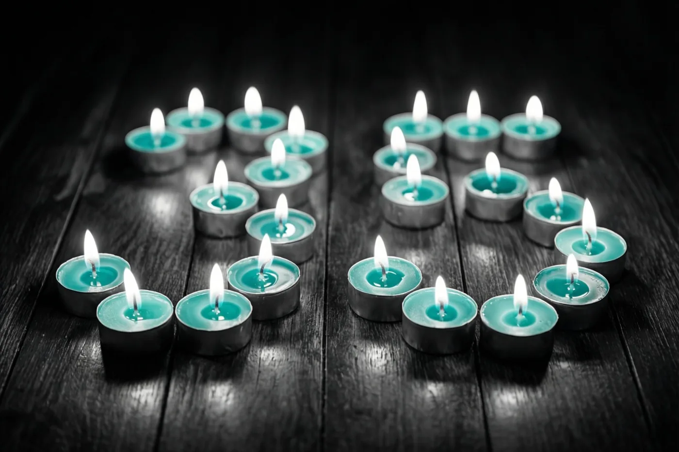 Brandende blauwgroene theelichtjes vormen 35 op een donkere houten vloer in een verder monochroom beeld.