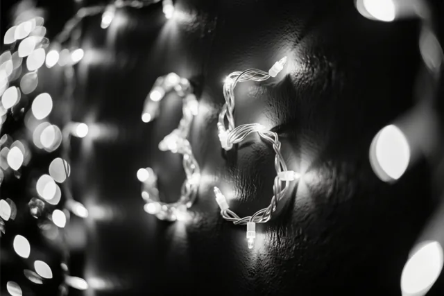 Lichtjes vormen het getal 35 op een donkere muur met structuur, met wazige feestlichtjes op de achtergrond.