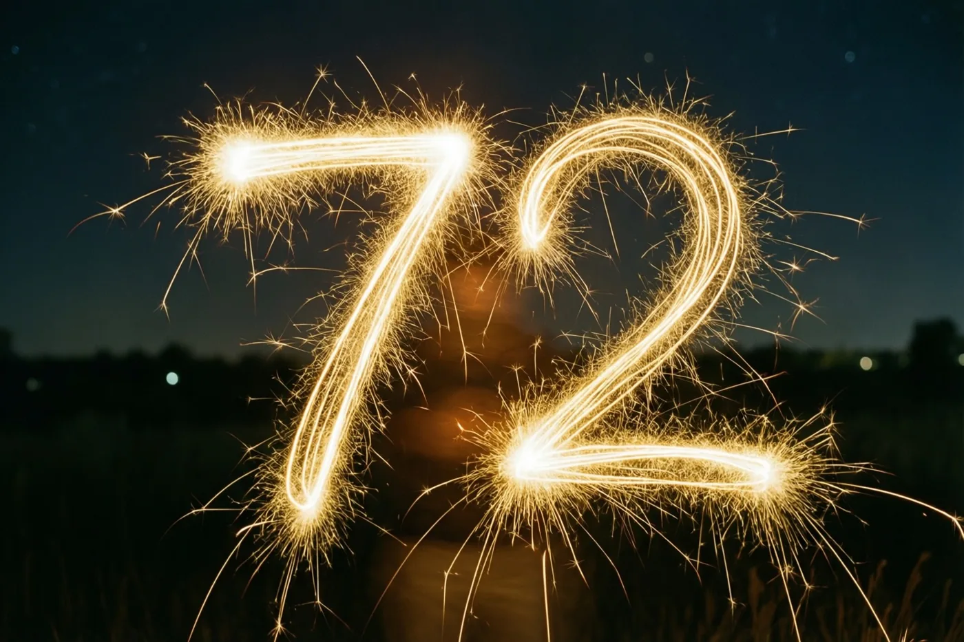 Gouden vonkensporen vormen 72 in de nacht, met onscherp gras en lichtjes in de verte.