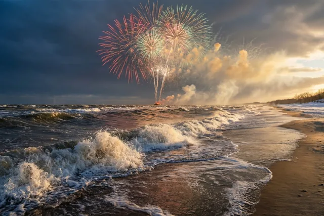 Vuurwerk barst open boven een stormachtig winterstrand waar brekende golven met wit schuim aanspoelen, in donkerblauwe en goudgele tinten.