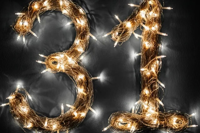 Warme lichtjes vormen 31 tegen een donkere muur, met onscherpe lichtvlekken rondom.