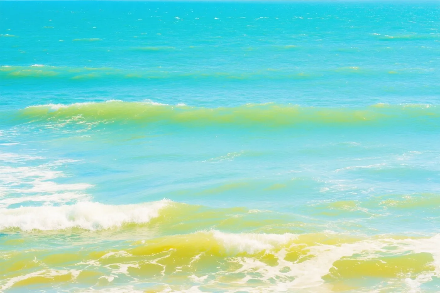 Zachte golven in turquoise, groen en wit rollen naar het strand aan de Belgische kust op een zonnige zomerdag.