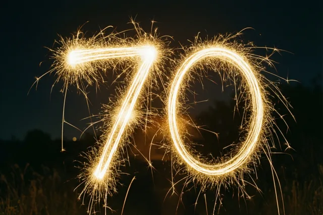 Gouden lichtsporen van sterretjes vormen 70 tegen een donkere nachthemel, met vage silhouetten van gras en bomen.